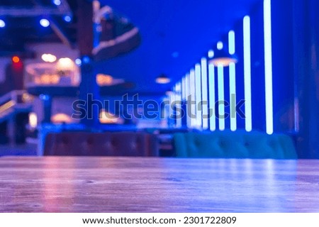 Selective focus on the table board of a restaurant nightclub modern design background in neon blue light. Royalty-Free Stock Photo #2301722809