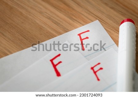 Bad grade F is written with red pen on the tests.  Royalty-Free Stock Photo #2301724093