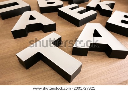 The white letters of the plexiglass logo are laid out on the table.Production of outdoor advertising. Creating an inscription from plastic with your own hands.