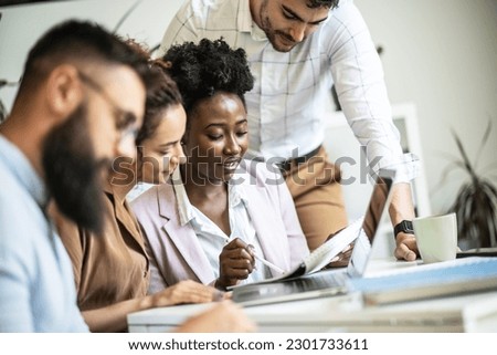 A diverse, casual design team collaborates in the office, creating innovative solutions and fostering in dynamic creative environment. Royalty-Free Stock Photo #2301733611