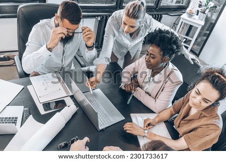 A diverse, casual design team collaborates in the office, creating innovative solutions and fostering in dynamic creative environment. Royalty-Free Stock Photo #2301733617