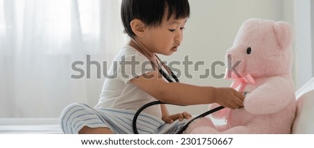 Young cute Asian girl Playing doctor with favorite toys. Sitting on the bed. little girl having fun. take care teddy bear Playing alone in the bedroom, future, dream, development, EF , IQ, EQ