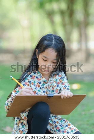 Cute girl sketching sitting on lawn.