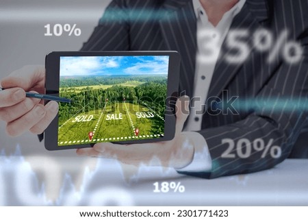 Sale of land. Realtor's hands with tablet. Snapshot of territory with caption sold. Realtor is selling land. Graph of rise in land prices. Investment in stead. Realtor sells building site Royalty-Free Stock Photo #2301771423