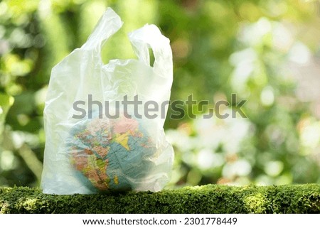 Planet earth put in a plastic bag on nature background. Royalty-Free Stock Photo #2301778449