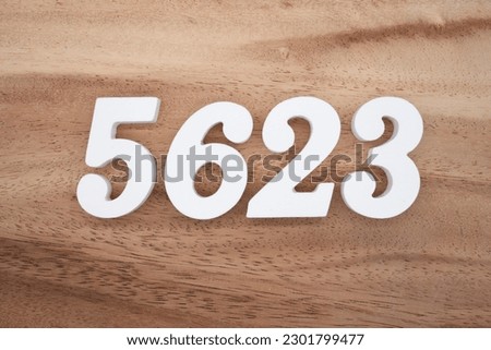 White number 5623 on a brown and light brown wooden background.