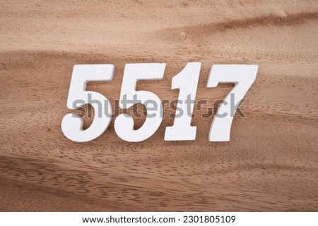 White number 5517 on a brown and light brown wooden background.