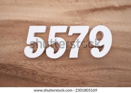 White number 5579 on a brown and light brown wooden background.