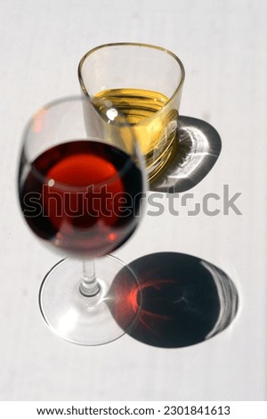 Minimal Visual Glass of Red Wine and Whiskey on White Background Table With Long Shadows Under Sunray Royalty-Free Stock Photo #2301841613