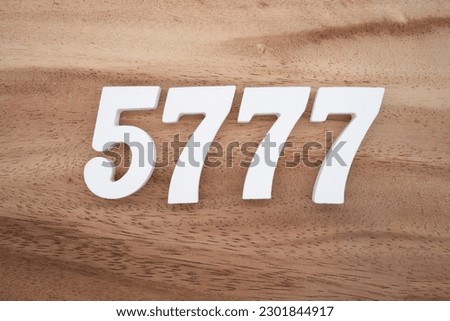 White number 5777 on a brown and light brown wooden background.