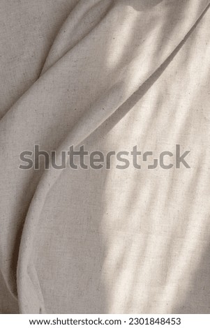 Draped beige linen fabric texture background with natural sunlight shadows. Neutral lifestyle bohemian backdrop