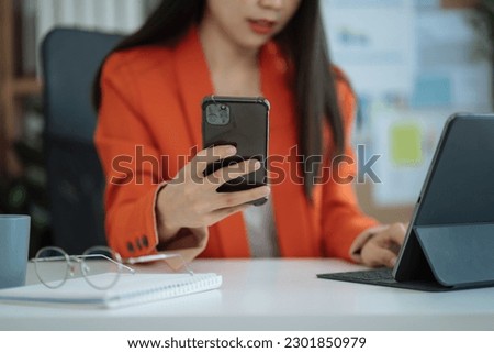 business woman using mobile phone surfing the internet, searching information during online working on laptop computer at home office.