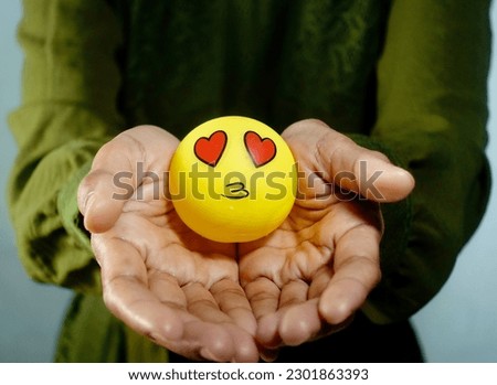 A hand holding yellow emoticon  rubber toys. Design for world emoticon day.  