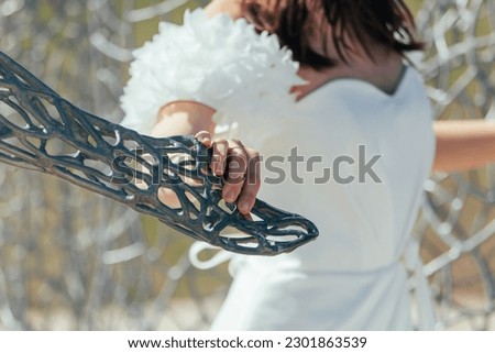 bride's hand on the background of the chain-link fence.