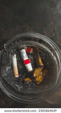 This image depicts cigarette butts placed in an ashtray. The grayish color and dirty appearance indicate that the cigarettes have been used and left in the ashtray for a long time.