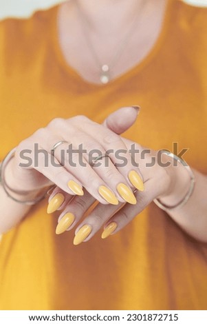 Female hand with long nails and a pale yellow manicure 