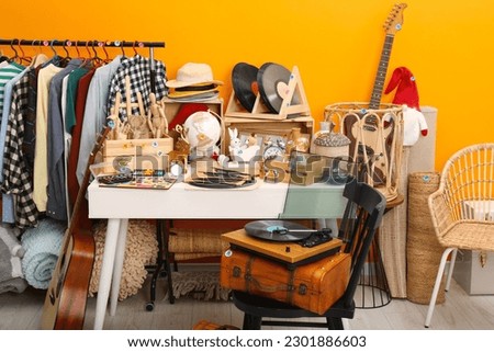 Many different stuff near orange wall indoors. Garage sale Royalty-Free Stock Photo #2301886603