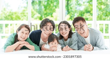portait of a three generation asian family looking at the camera lying together on the bed. Royalty-Free Stock Photo #2301897305