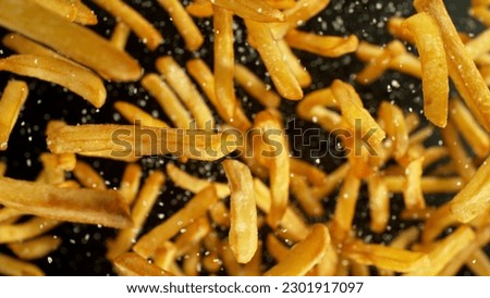 French fries - fried potatoes flying. Fly fastfood isolated on black background. Royalty-Free Stock Photo #2301917097