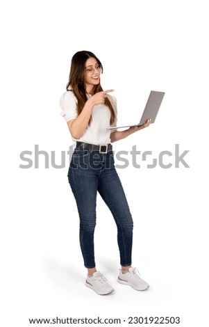 Woman pointing laptop, full body studio shot of beautiful woman pointing laptop. Standing over isolated white background. Banner design concept idea. Recommending web site. Looking notebook, smiling.