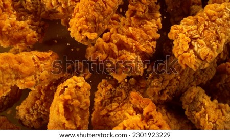 Freeze Motion Shot of Flying Fresh Fried Chicken Wings or Strips, Close-up Royalty-Free Stock Photo #2301923229