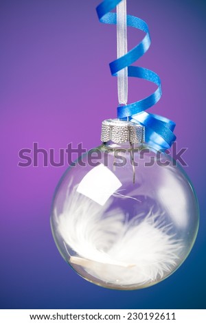 Close up of a glass Christmas decoration ball against purple background.