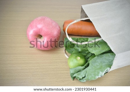 Vegetables in the paper bags on wooden background.