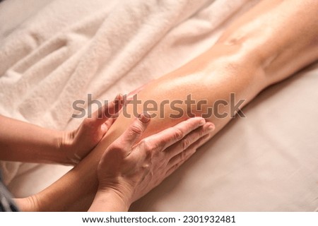 Skilled masseuse giving leg massage to client