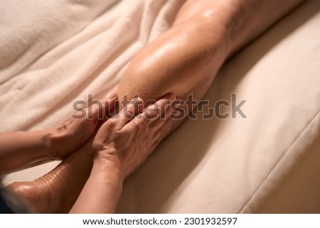 Professional spa therapist giving leg massage to male client