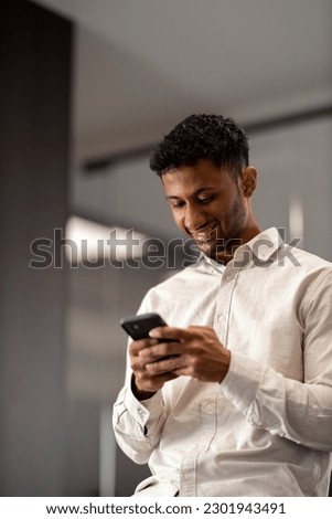Portrait of a young multiethnic businessman using his smartphone in the office.