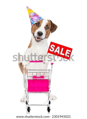Jack russell terrier puppy wearing party cap pushing a shopping cart and showsing signboard with labeled "sale". isolated on white background