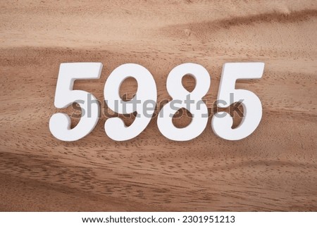 White number 5985 on a brown and light brown wooden background.