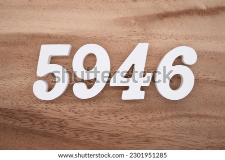 White number 5946 on a brown and light brown wooden background.
