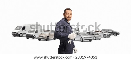 Auto mechanic holding a wrench and standing in front of parked vans and cars isolated on white background Royalty-Free Stock Photo #2301974351