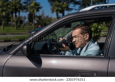 Hidden photographing. Paparazzi Concept Photographer uses his professional camera. Private detective man in car window. Mobile reporter. Photojournalist at work. Detective or investigator.