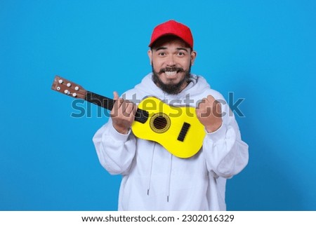 expression of asian man wearing hoodie jacket holding ukulele