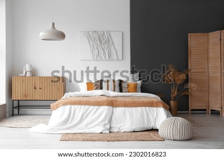 Interior of stylish bedroom with cozy bed and wooden cabinet Royalty-Free Stock Photo #2302016823