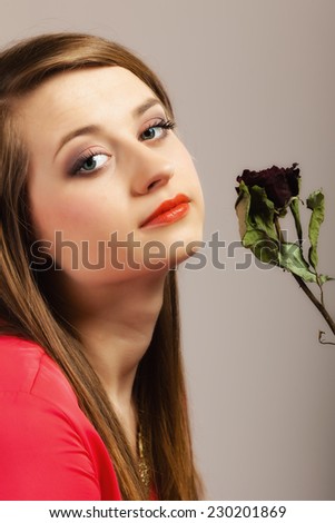 Portrait beautiful fashion woman teen girl in red gown with dry rose on gray background