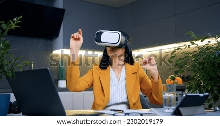 Portrait of likable confident concentrated successful adult dark-haired woman in stylish jacket which working on virtual screen in special 3d glasses at home Royalty-Free Stock Photo #2302019179