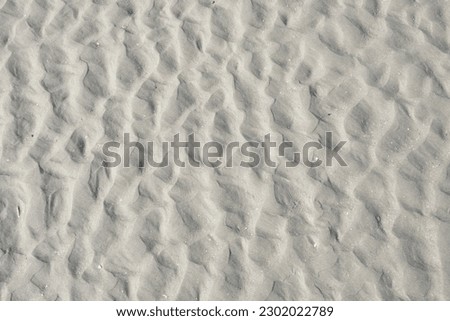 Chaotic pattern of ripples in the sand of the beach, caused by waves and the movement of water