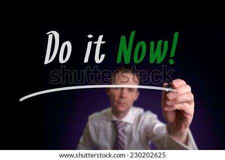 A businessman writing Do it Now on a screen. Business Concept.