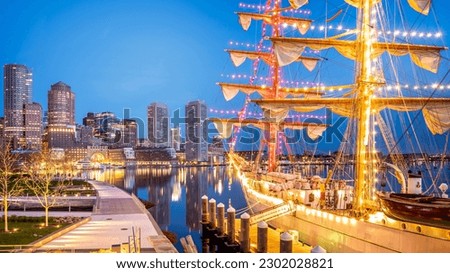 View of the historic architecture of Boston in Massachusetts, USA at the Fan Pier Waterfront at sunrise with the skyscrapers and a sailing boat anchored on the side pier.