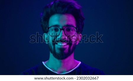 Portrait Indian man Muslim guy developer coding worker smile computer internet technology hacker Arabian male in glasses smiling neon blue ultraviolet studio background high-tech future cyberspace Royalty-Free Stock Photo #2302032667
