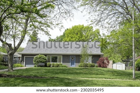 Tree Surrounded Gray House with Flowering Lilac Bush