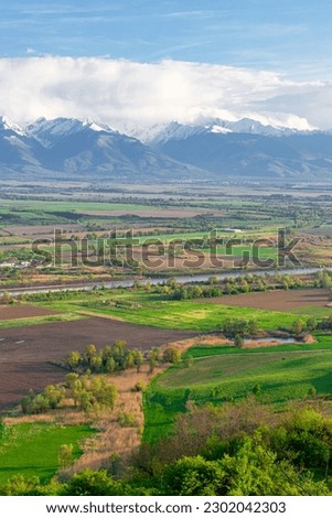 Photography of the beautiful Transylvanian landscape with countryside crops, lake and Fagaras mountains in the background. Photography was taken from a higher ground using a wide angle lens.