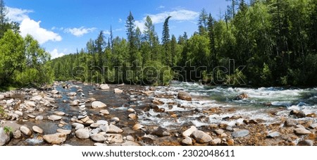Summer landscape with fast river with stone pyramid of tourists and green forest along banks on sunny day. Natural summer background. Panorama. River Ekhe-Ukhgun, Nilovka, Tunka valley, Buryatia Royalty-Free Stock Photo #2302048611