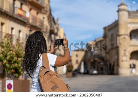 Woman tourist photographer with big backpack taking photo of Town Hall 16th Century in Ciudad Rodrigo  in Salamanca. Travel and hobby concept