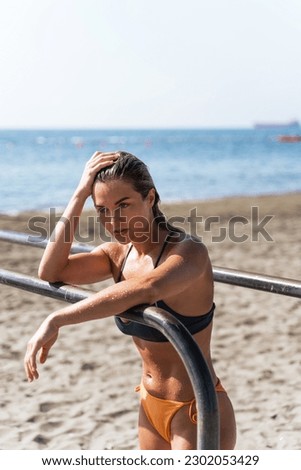 Exhausted woman athlete resting during her workout at a beach gym.