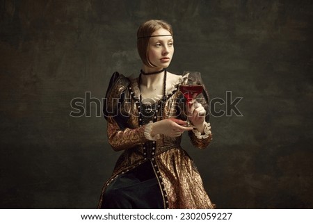 Portrait of pretty, young girl, princess in vintage dress drinking red wine against dark green background. Celebration, degustation. Concept of history, renaissance art remake, comparison of eras Royalty-Free Stock Photo #2302059227