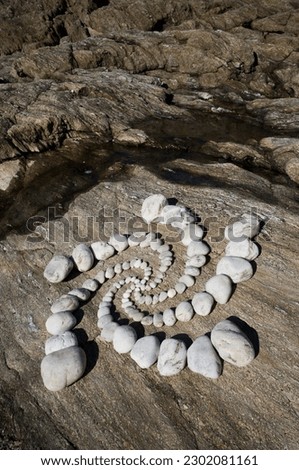 Five-armed esoteric spiral of white pebbles on a rock background landscape landart
